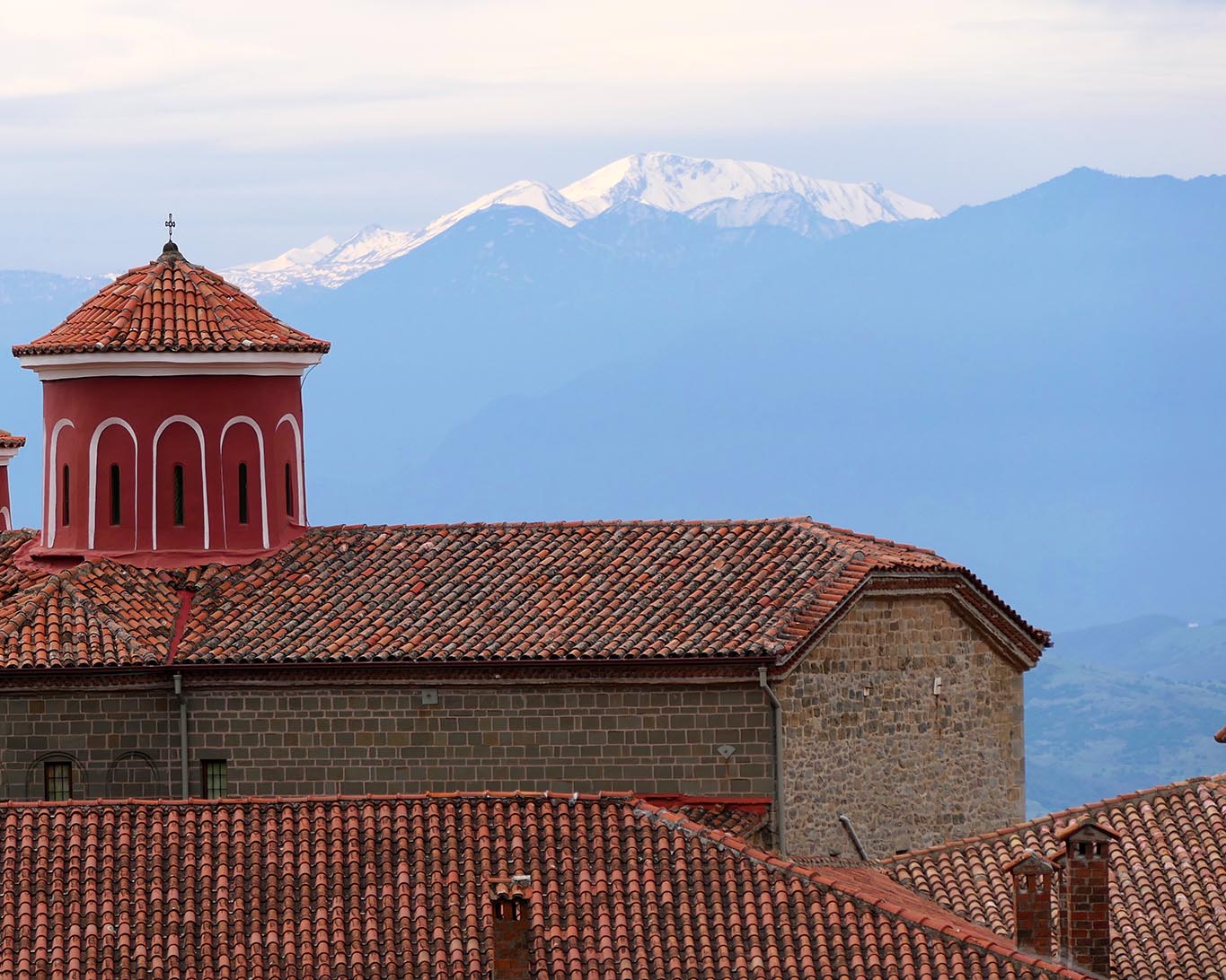 Der berühmte rote Turm und die schneebedeckten Berge mit dem Garten des Meteora-Klosters Agios Stephanos