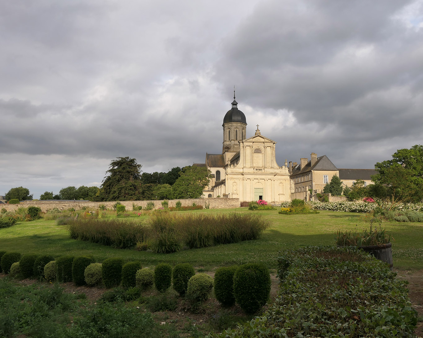 Dramatisches Licht wirft der Himmel der Normandie auf die Abbaye Mondaye und ihren Klostergarten.