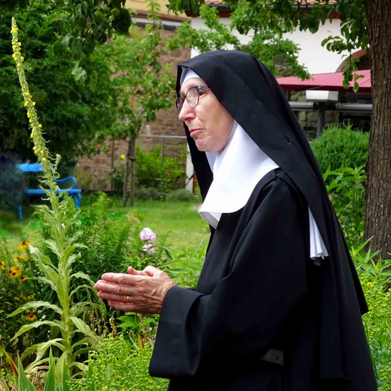 Schwestern Christa bei einer Gartenführung erklärt ihren Gästen ausführlich den biologischen Gartenbau.