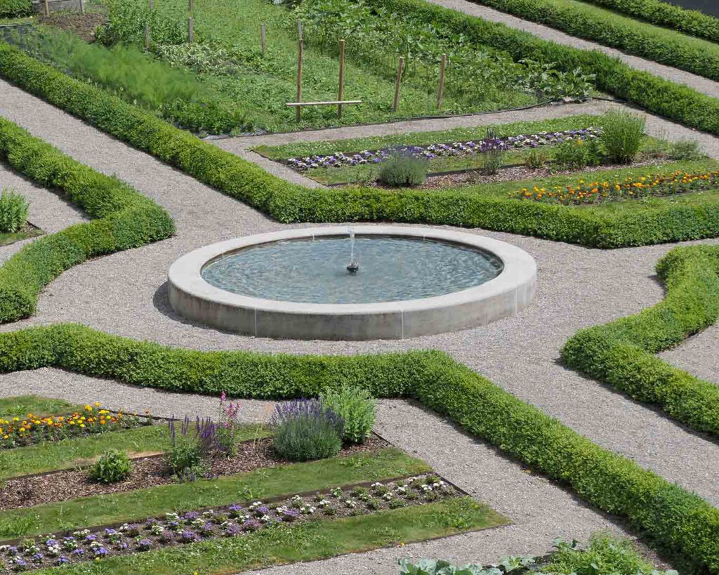 brunnen bunt, barocke Formen müssen nicht kitsch- und prunkgetrieben sein. Dem Negativbeispiel einiger österreichischer Klöster wurde bei der Neuanlage dieses Gartens nicht gefolgt. Die kreuzenden Wege symbolisieren die vier Himmelsrichtungen