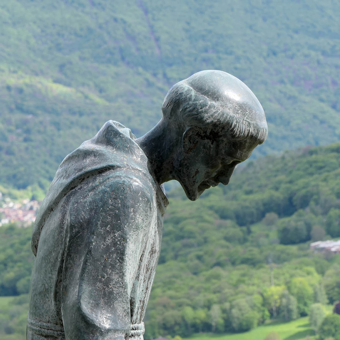 Statue am Convento in Bigorio welche den Heiligen Franz von Assisi darstellt mit leicht gebeugter Körperhaltung.