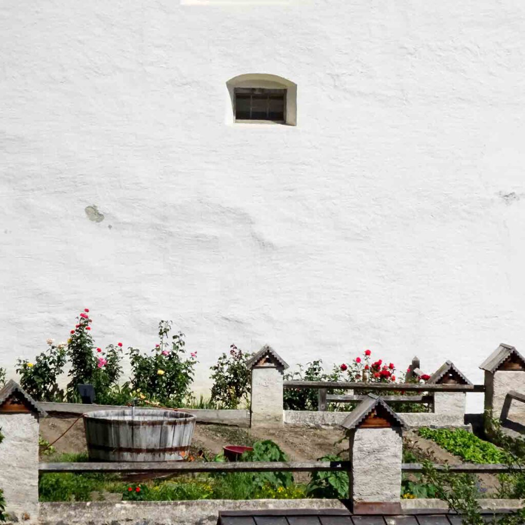 garten mit bottich benediktiner stift marienberg Nur die Rosen schmiegen sich an die weissen Mauern des Klosters. Wasservorrat und Tränke