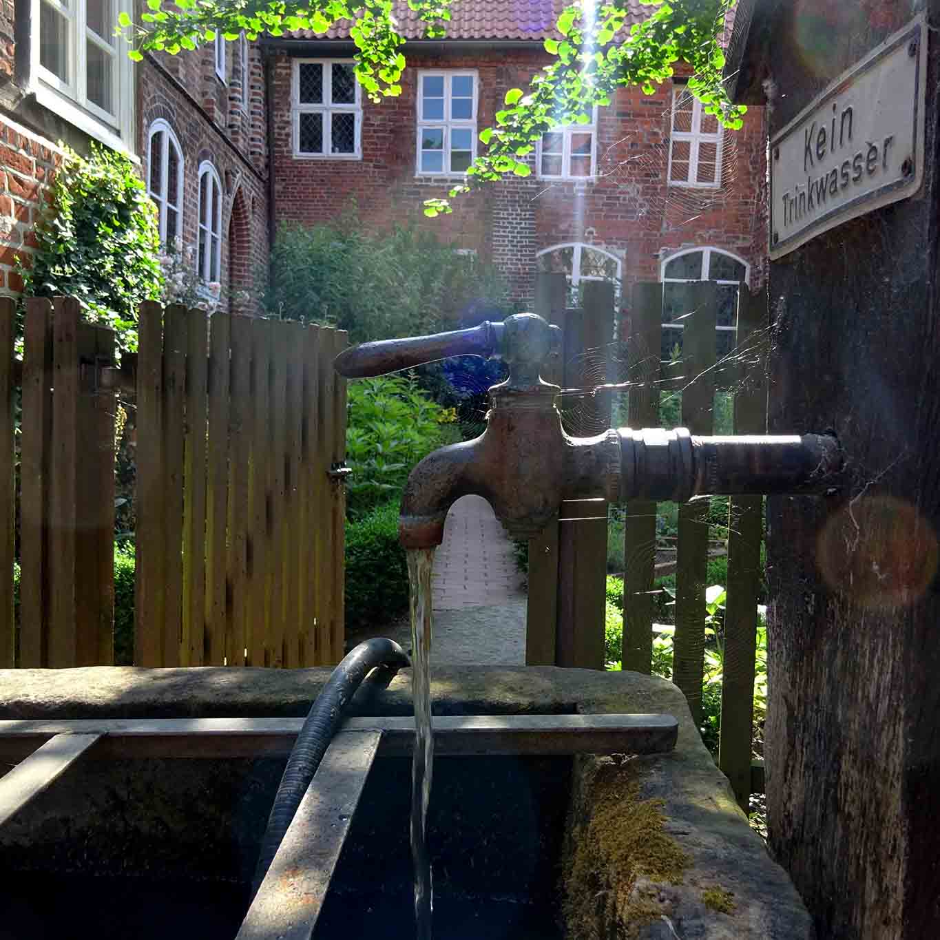 Plätschernder Wasserhahn mit Kräutergarten im Kloster Lüne.