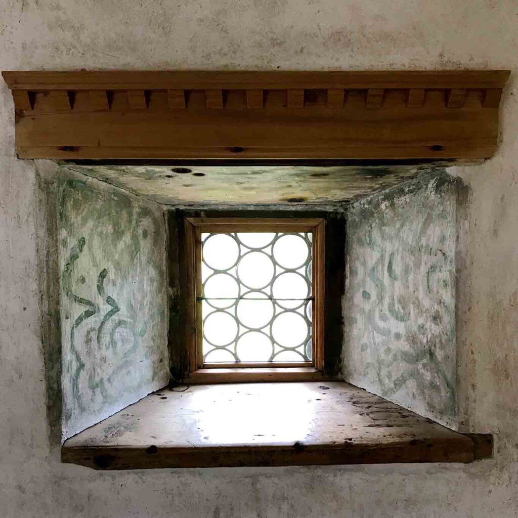 Dicke Mauern aus romanischer Zeit. kloster muestair bleiglasfenster mit malerei am sockel