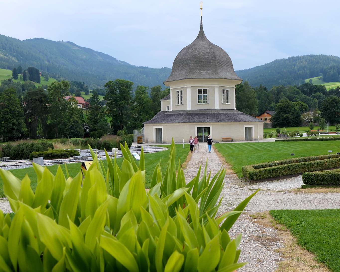 Spaziergänger queren den Kreis rund um den Pavillon des Klostergartens des Benediktinerstifts St. Lamprecht.