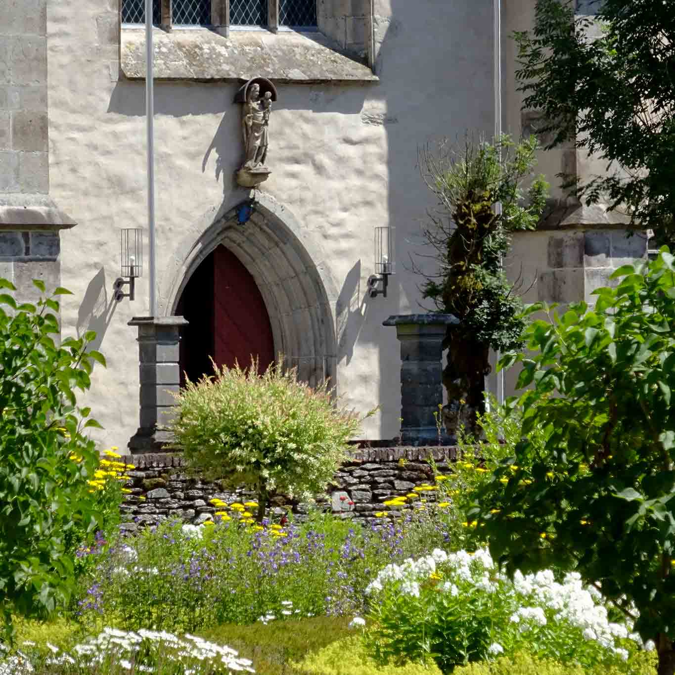 Maria mit dem Jesuskind schaut auf eine wunderschöne Gartenlandschaft. zisterzienser abtei marienstatt kirchentür