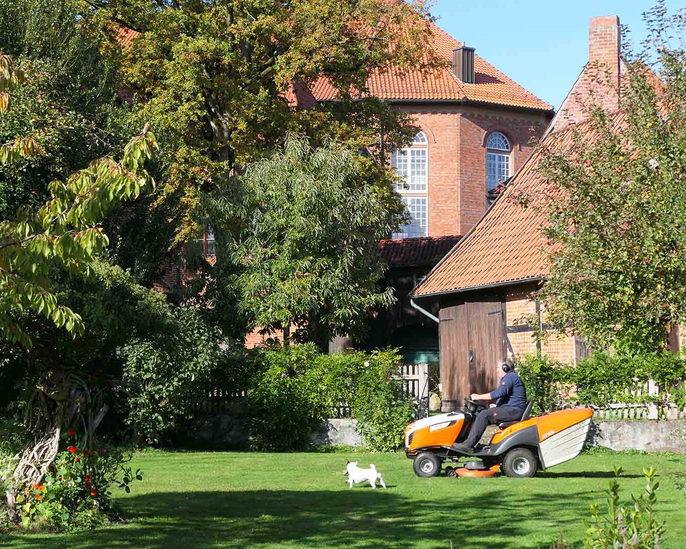 Der Gärtner und sein Hund drehen ihre Runden auf dem Rasenmäher durch den Klostergarten.